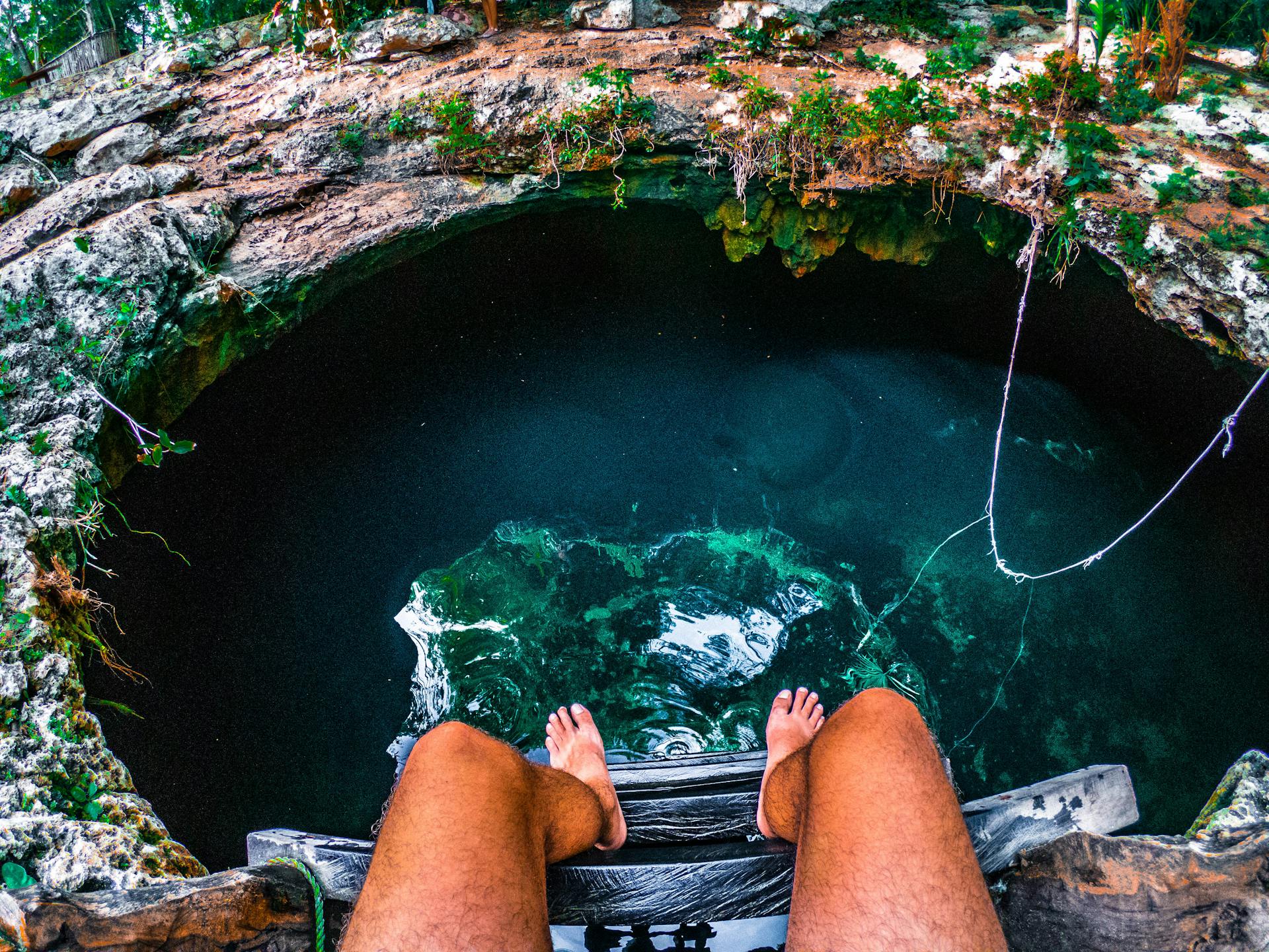 Person Sitting on a Ladder With View Of Underground Water - Tulum, Mexico