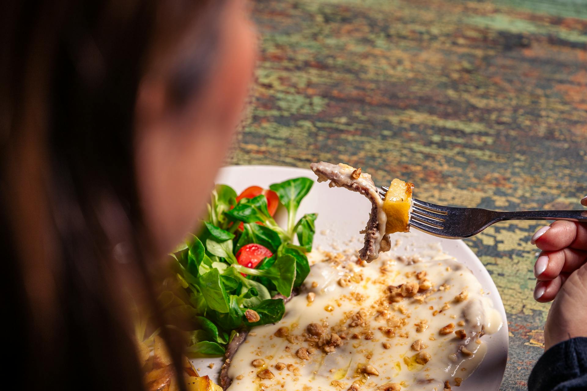Person Enjoying Creamy Beef Meal with Fresh Salad