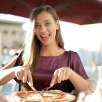 Woman in Purple Top While Slicing Pizza