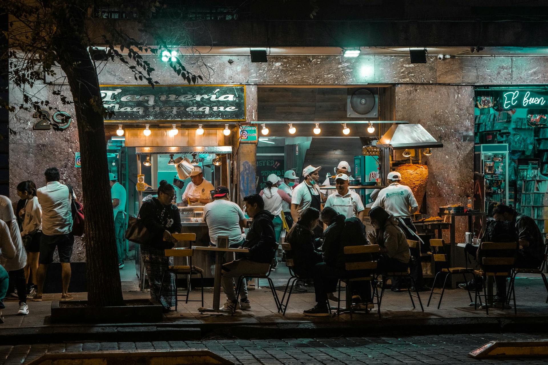 People Sitting at the Tables Outside of a Restaurant in City in the Evening