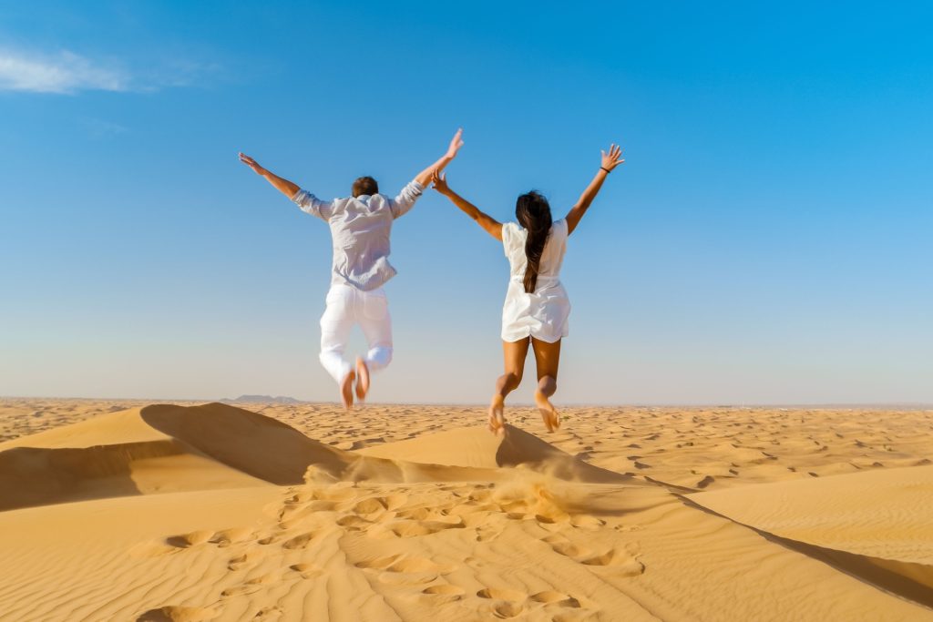 Couple on a Safari trip to the Sand dunes of Dubai United Arab Emirates, sand desert on a sunny day in Dubai.