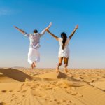 Couple on a Safari trip to the Sand dunes of Dubai United Arab Emirates, sand desert on a sunny day in Dubai.