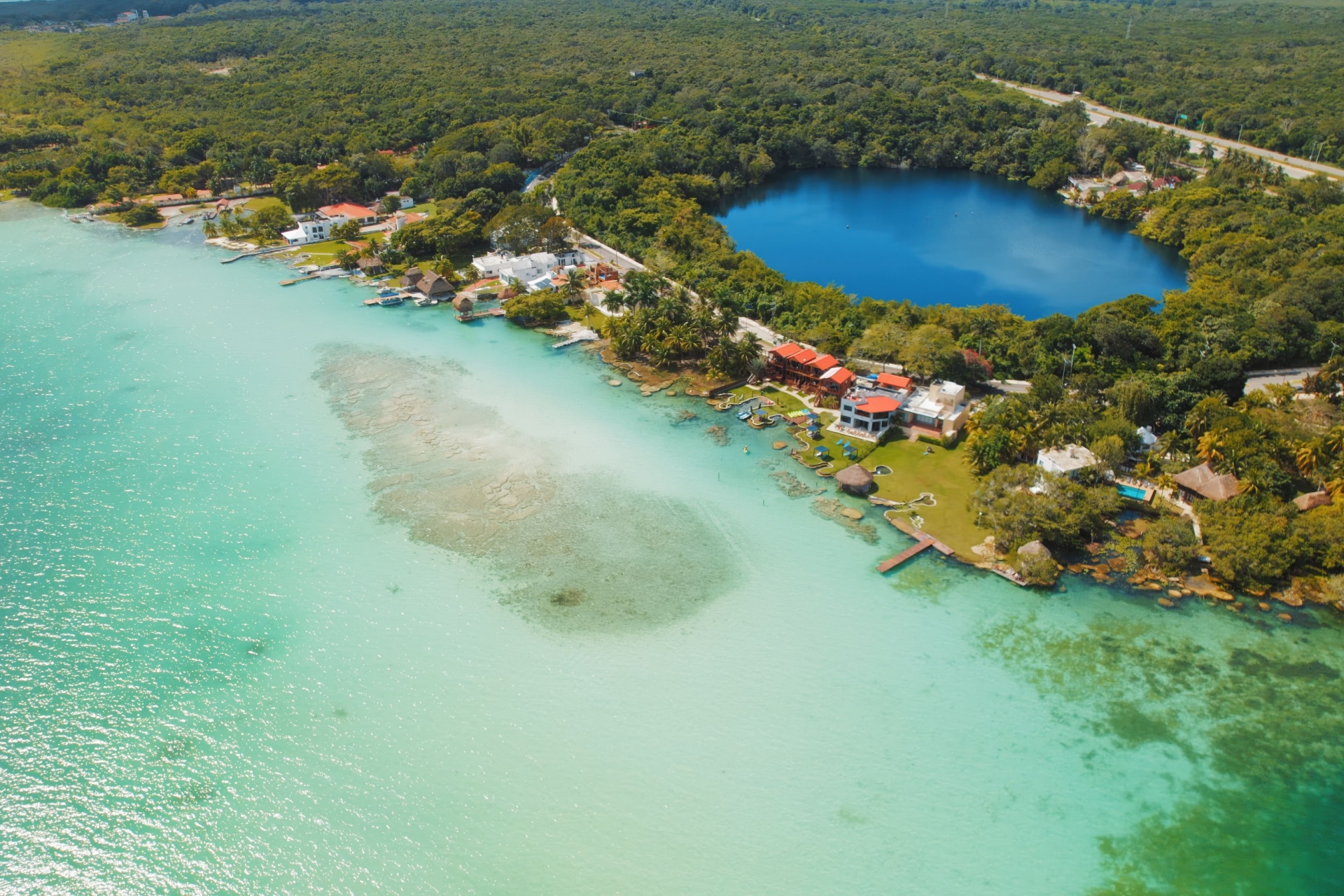 Aerial view of Bacalar lagoon and Cenote Azul with contrasting blue water shades.