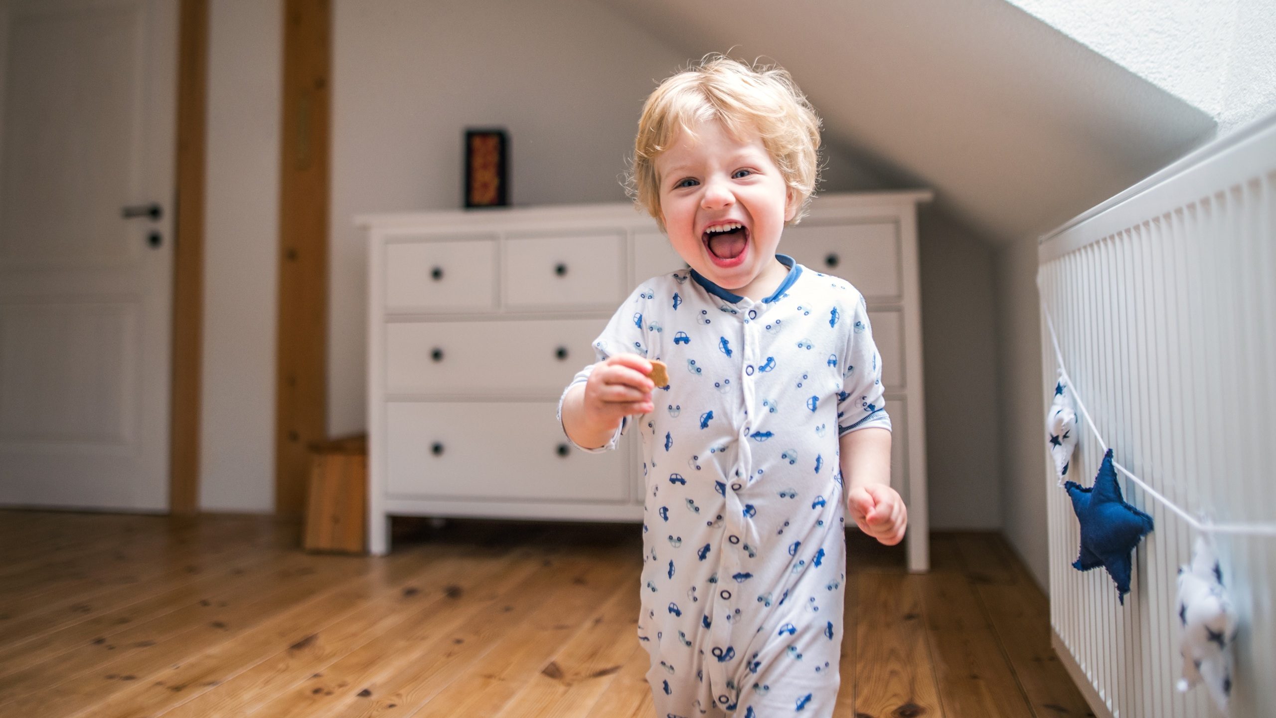 A toddler boy in the bedroom at home.