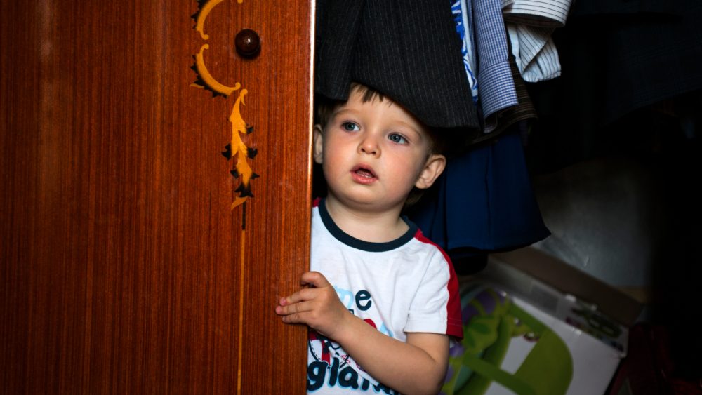 Little boy hiding inside wardrobe