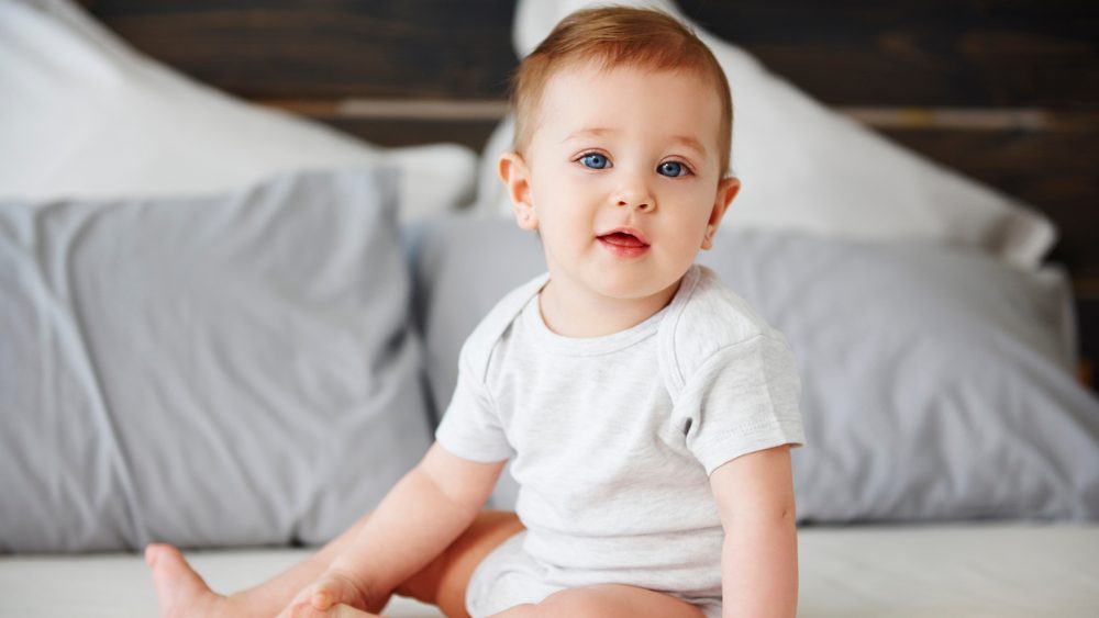 Portrait of cute baby sitting on bed