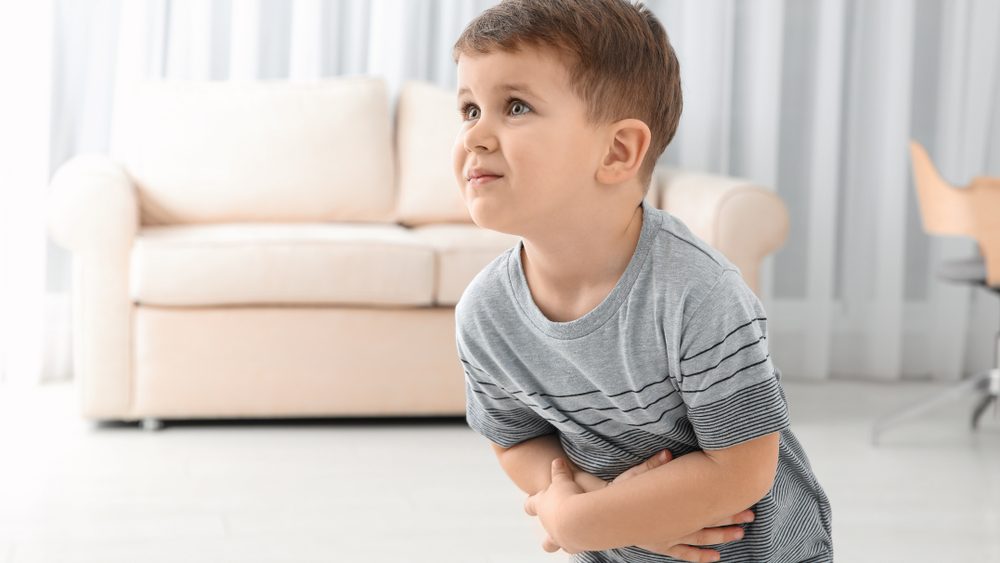 Little boy suffering from nausea in living room