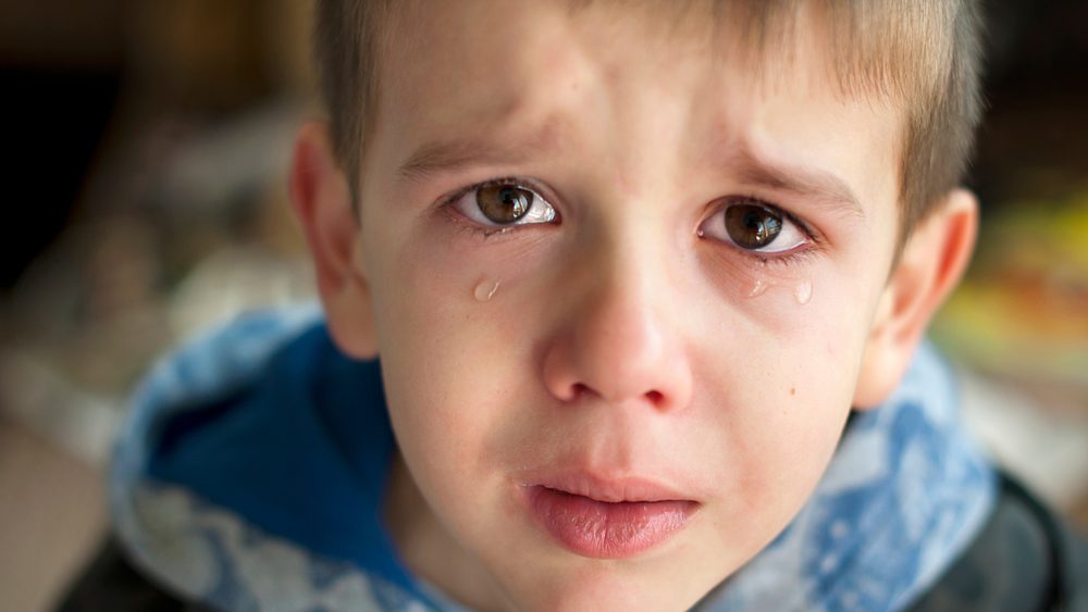 Sad child who is crying. A child with tears in his eyes looking at the camera. Close up