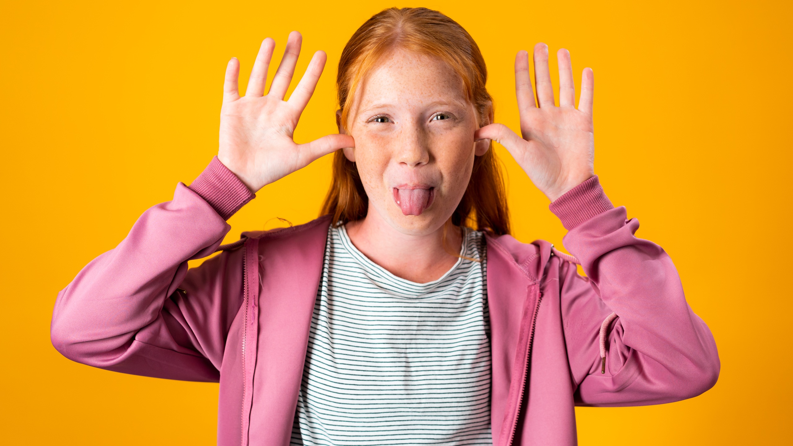 Red hair girl taunting and mocking while sticking her tongue out. Young Caucasian pre teen girl being rude and making funny faces with her tongue and hands.