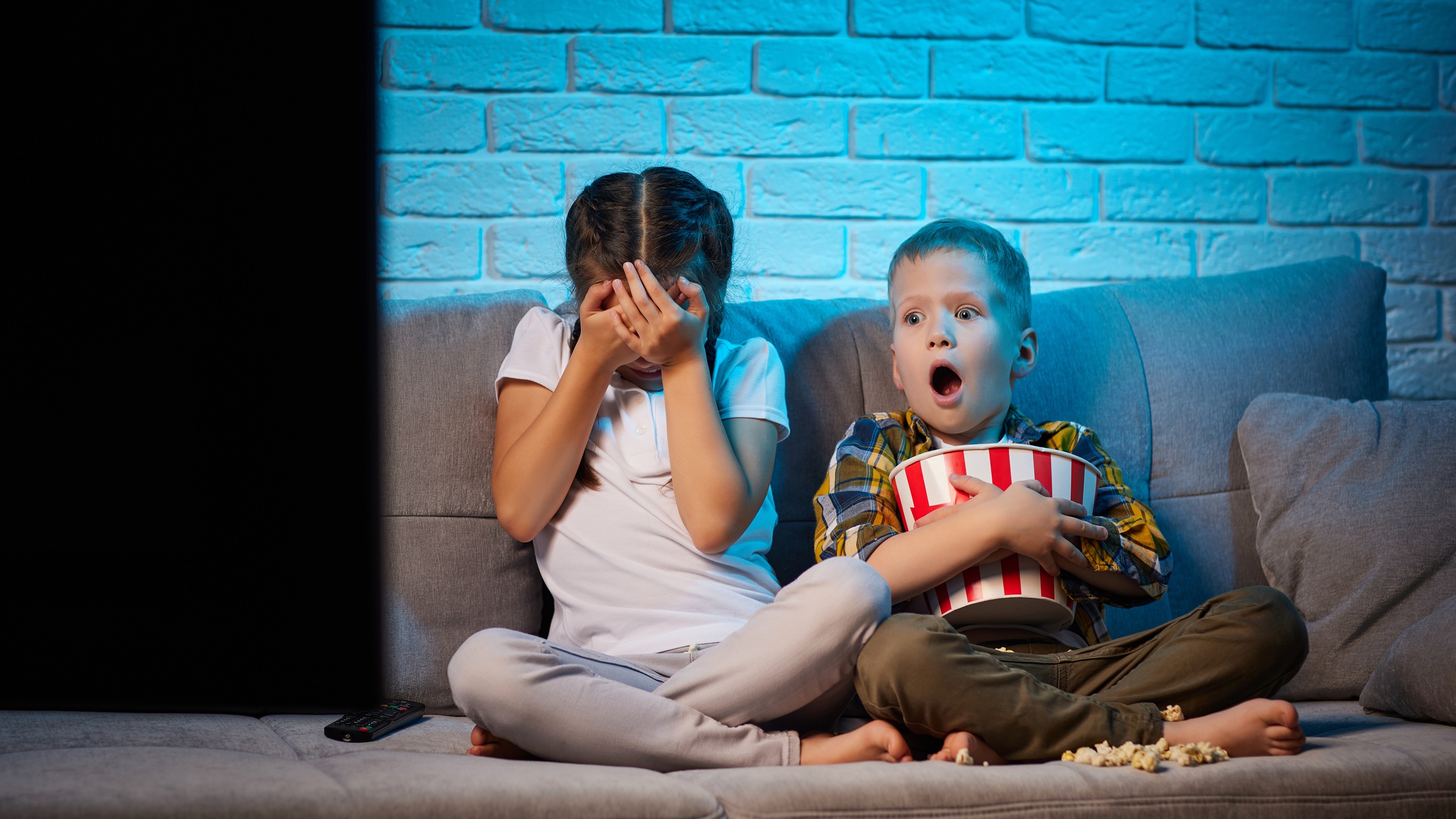 Two children with remote control watching TV
