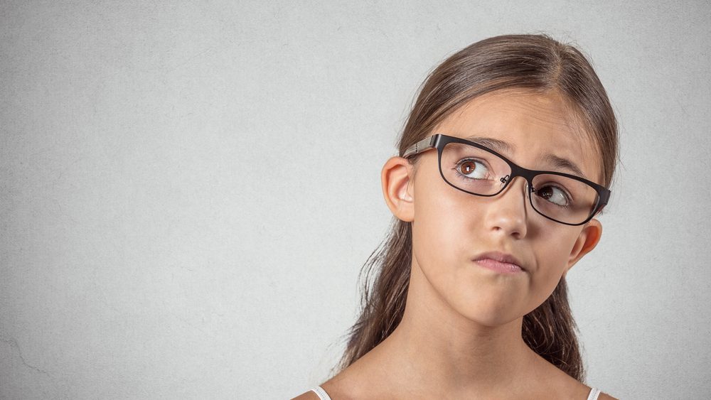 Closeup portrait skeptical young girl looking up, suspicious, skepticism on face, disapproval isolated grey wall background. Negative human emotions, facial expressions, feeling attitude body language