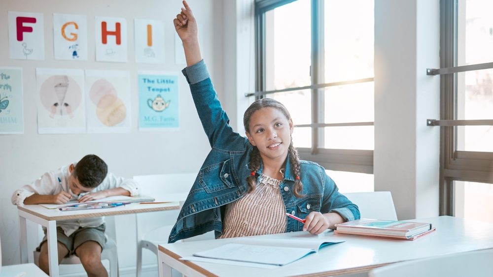 Education, black girl in class and question with hand in air, studying and learning for knowledge, answer or excited. African American female, young kid or child with arm raised for asking and growth