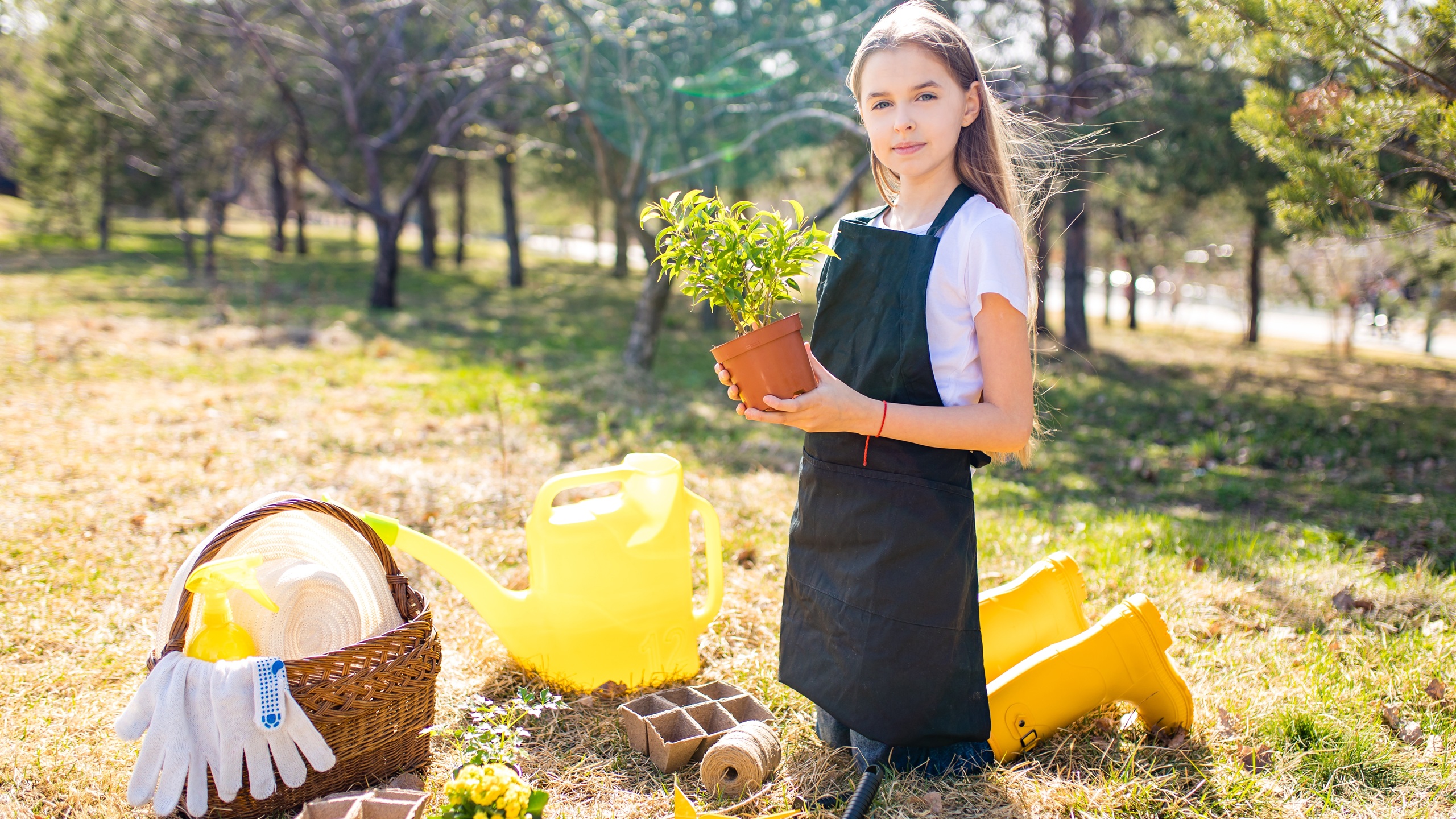 beautiful teen age girl in black apron and yellow rubber shoes in garden nature and care