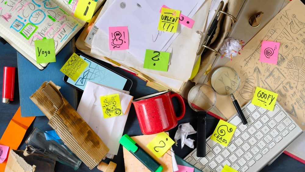 Messy workplace,chaotic office, overworked, bureaucracy,red tape concept with grungy desk,sticky notes and various office supplies, chaotic mess.