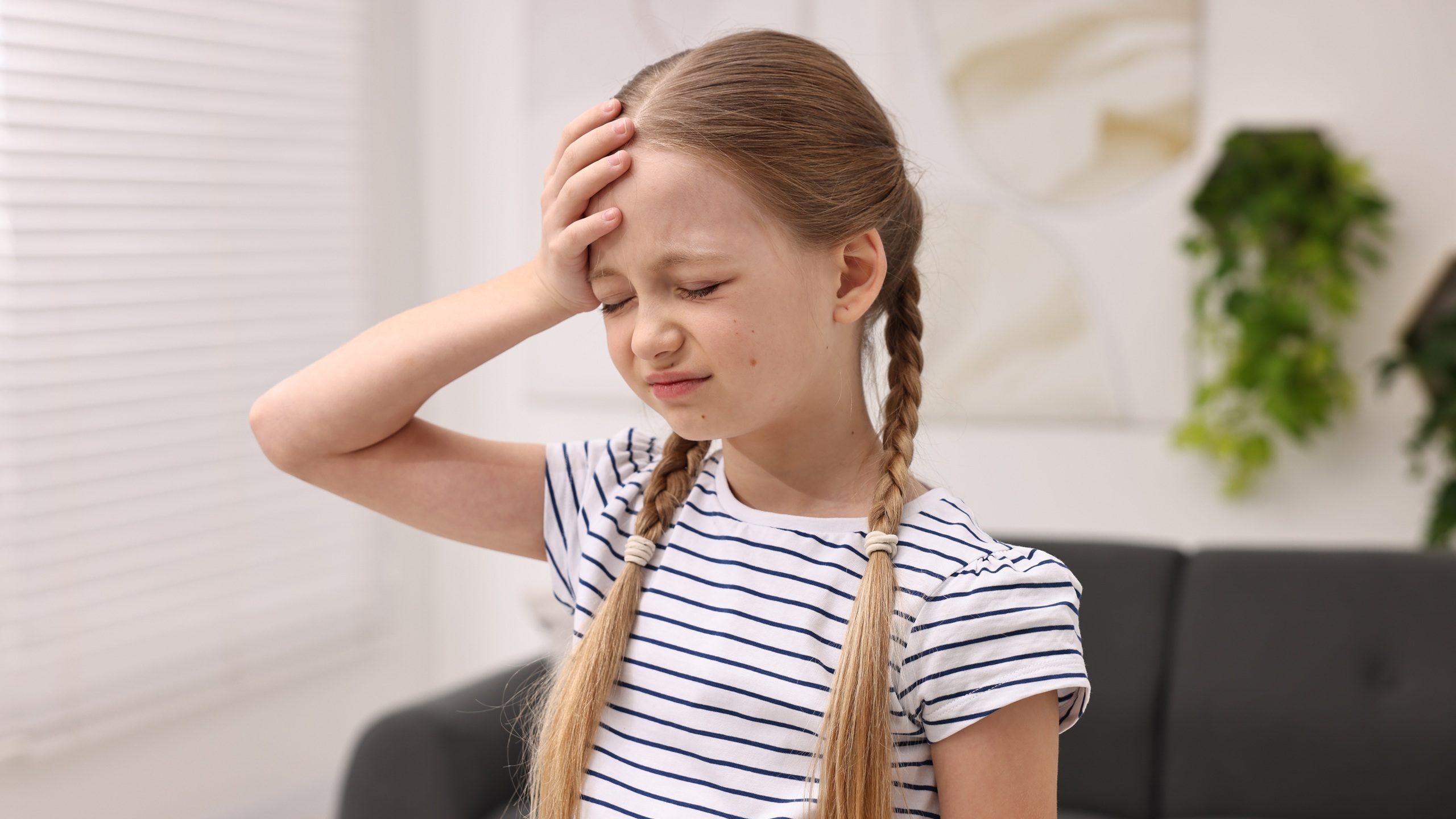 Little girl suffering from headache at home