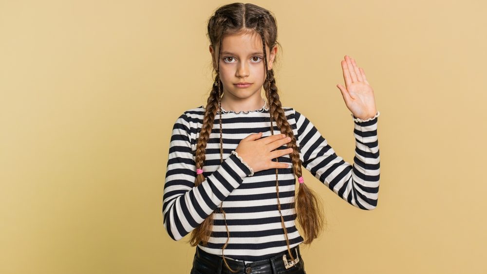 I swear to be honest. Sincere responsible preteen child girl kid raising hand to take oath, promising to be honest, to tell truth, keeping hand on chest, justice. Teenager children on beige background