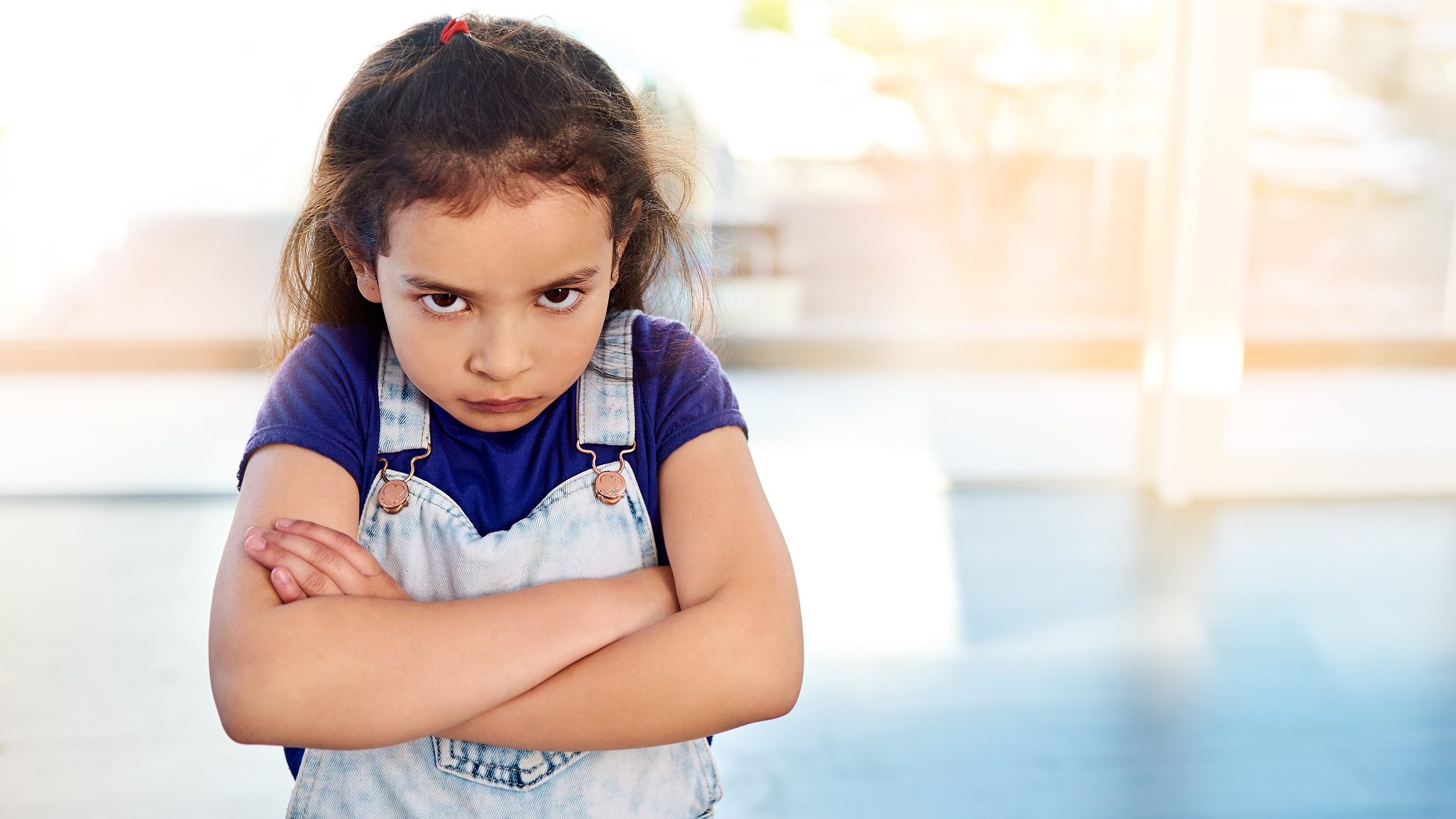 Female child, portrait and angry in house with arms crossed for frustrated, naughty and decision. Girl, upset and facial expression in home with flare for rebel, tantrum and punishment by parents
