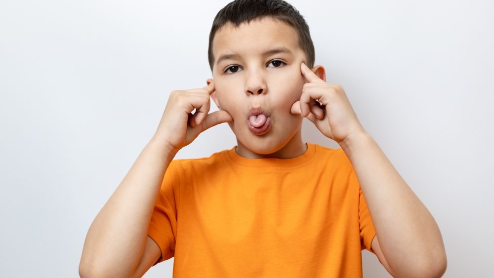 The guy raises his hands and shows his tongue. Sincere children's emotions.