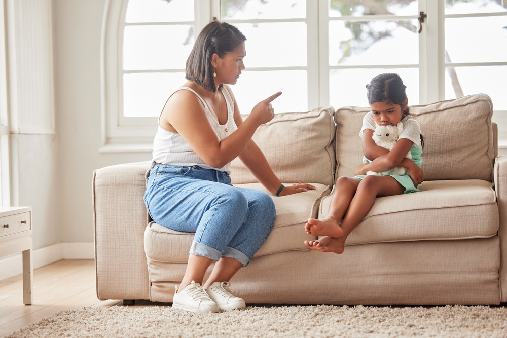 Angry mother, discipline and naughty child with bad behaviour for tantrum, guilt or disobedience on sofa at home. Frustrated mom talking to rude daughter, kid or little girl with difficult attitude