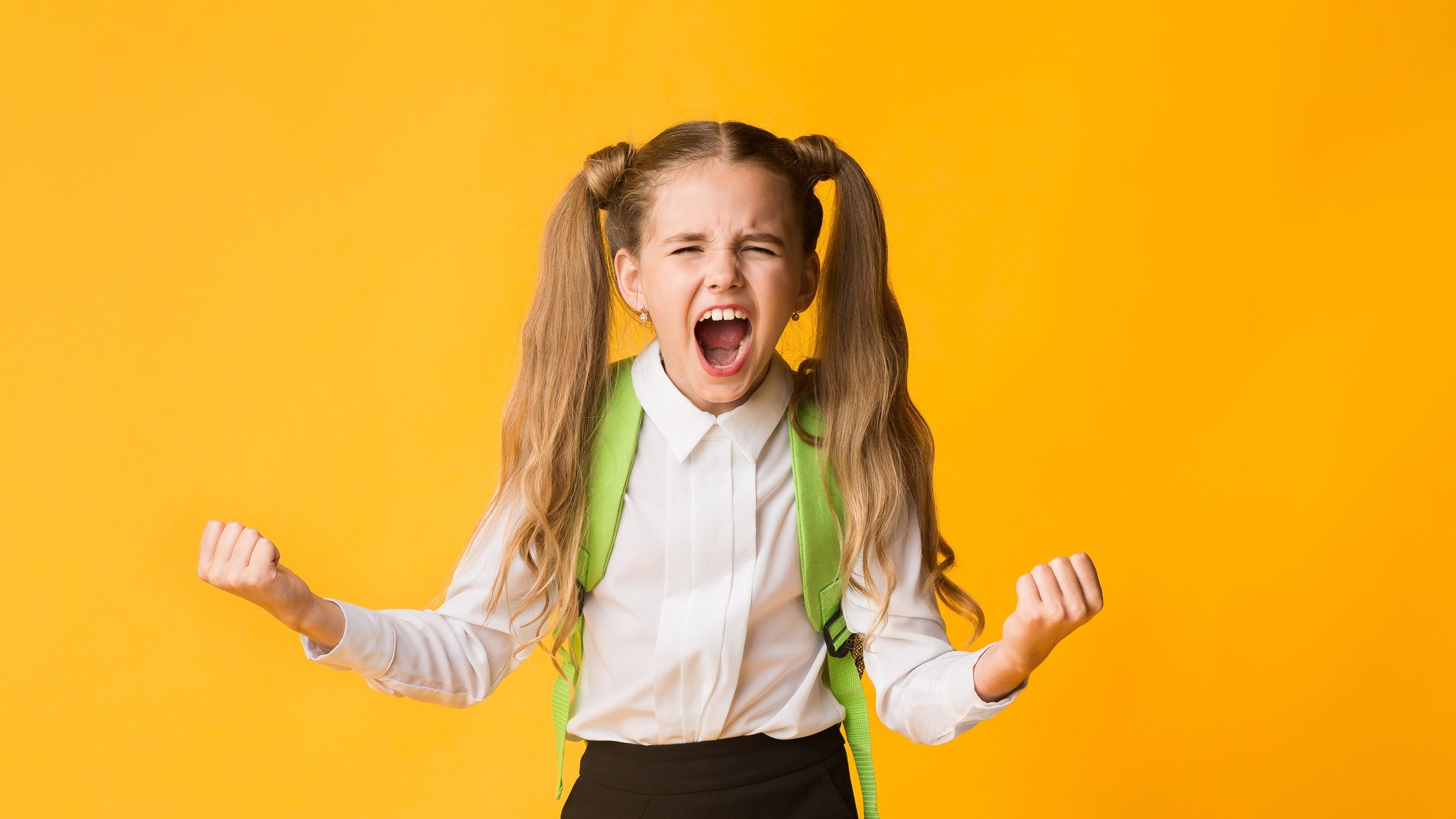 Crazy Angry Schoolgirl Shouting Furiously Over Yellow Studio Background. Free Space