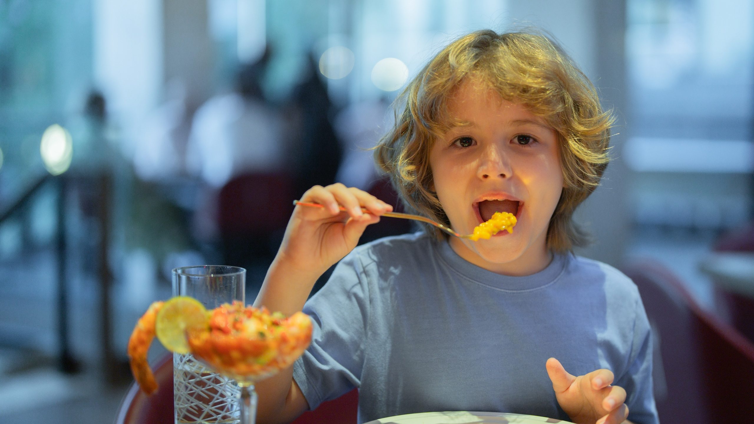Little boy eating seafood in restaurant. Kid eat Food fish gourmet seafood shrimp in restaurant. Adorable little boy at restaurant having breakfast.