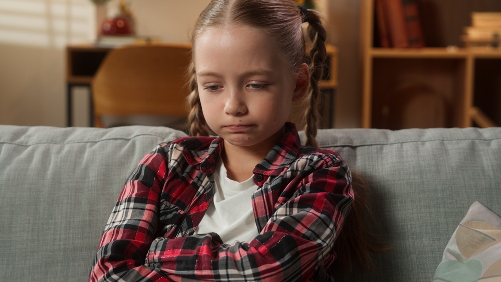 Portrait at home serious sad upset frustrated offended lonely Caucasian little girl female daughter adopt custody child kid teenager at couch problem domestic violence boring family trouble bad mood
