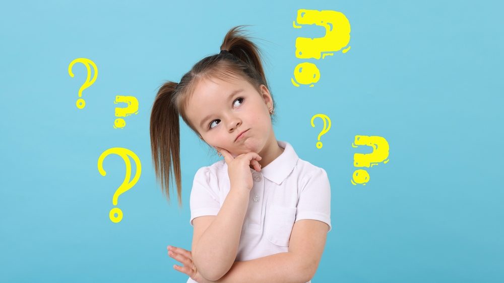 Confused little girl on light blue background. Yellow question marks near child