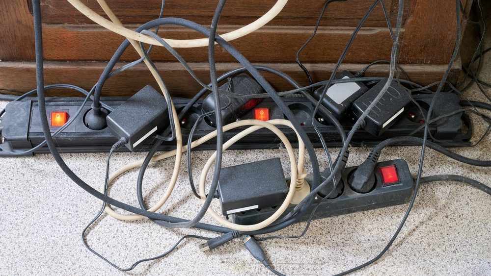 Lot of messy cables on the floor near wooden desk