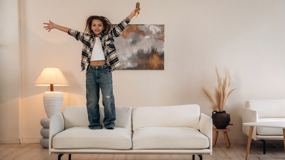 Dancing on the sofa. Cute little girl is in the domestic room alone.
