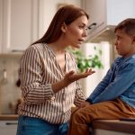 Mother scolding her son in the kitchen. Copy space.