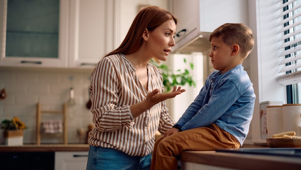 Mother scolding her son in the kitchen. Copy space.