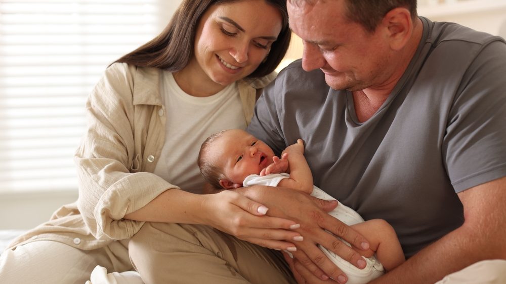 Happy parents with their newborn baby at home, closeup