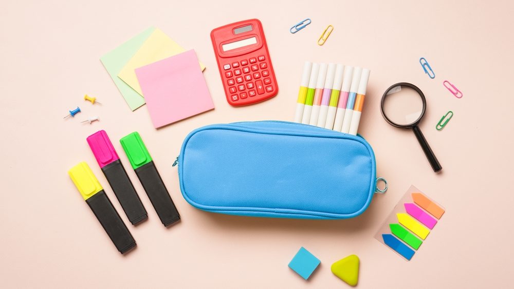 Pencil case, markers, pens, calculator and other stationery. Flat lay image.
