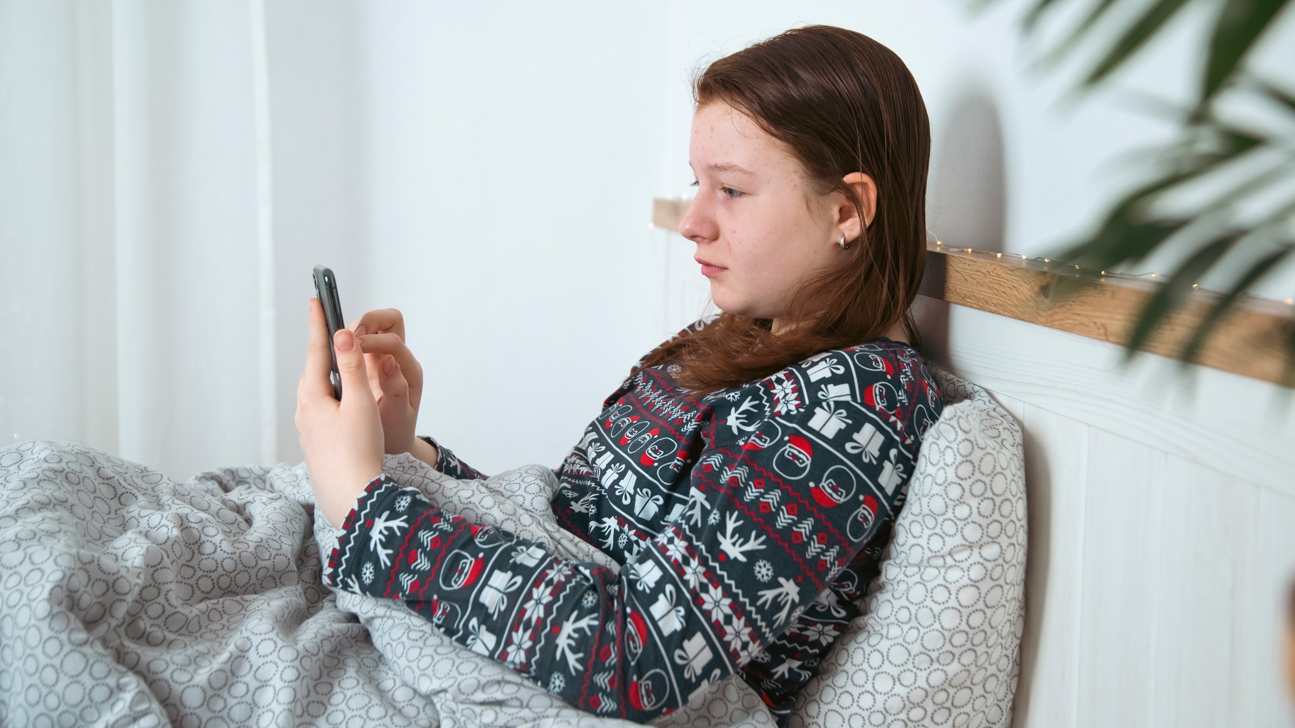 Teen girl using smart phone, tablet lying in bed late at night.Children's screen addiction concept.