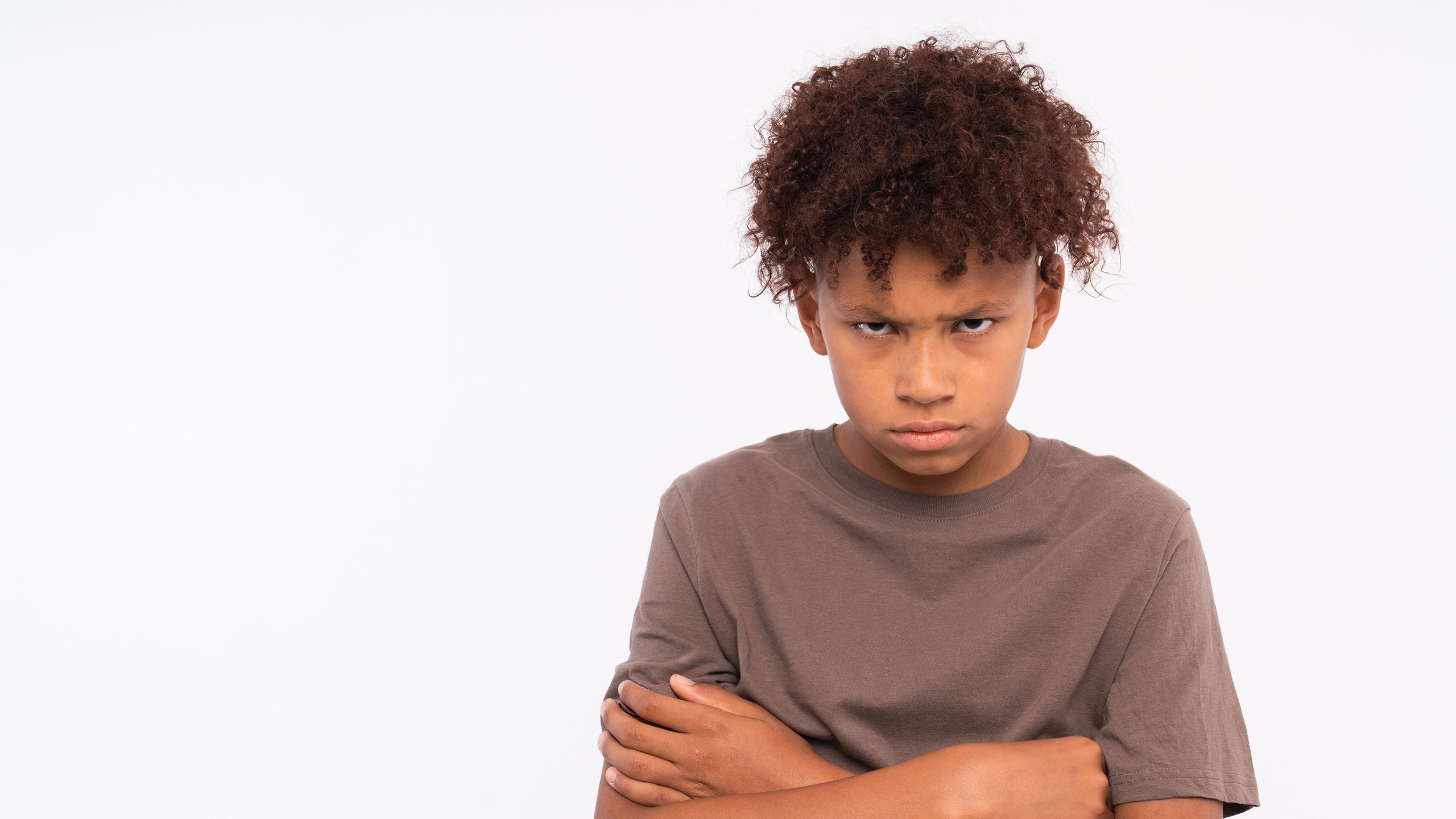 Isolated image of emotional Afro American schoolboy frowning brows and opening eyes wide expressing displeasure, bewilderment, having perplexed look. Human facial expressions, feelings and reaction