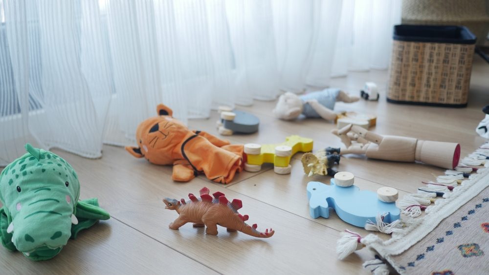 Colorful toys scattered on a wooden floor near a window