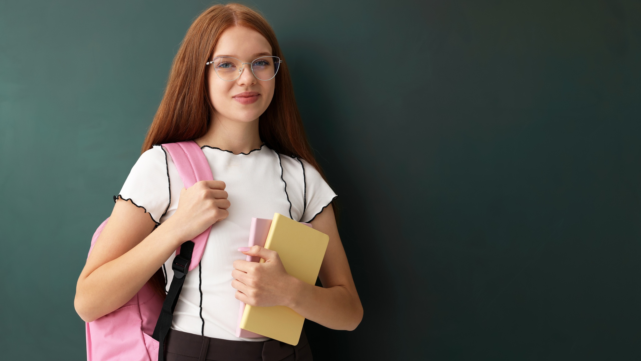 Back to school. Student with backpack and books near green chalkboard indoors, space for text