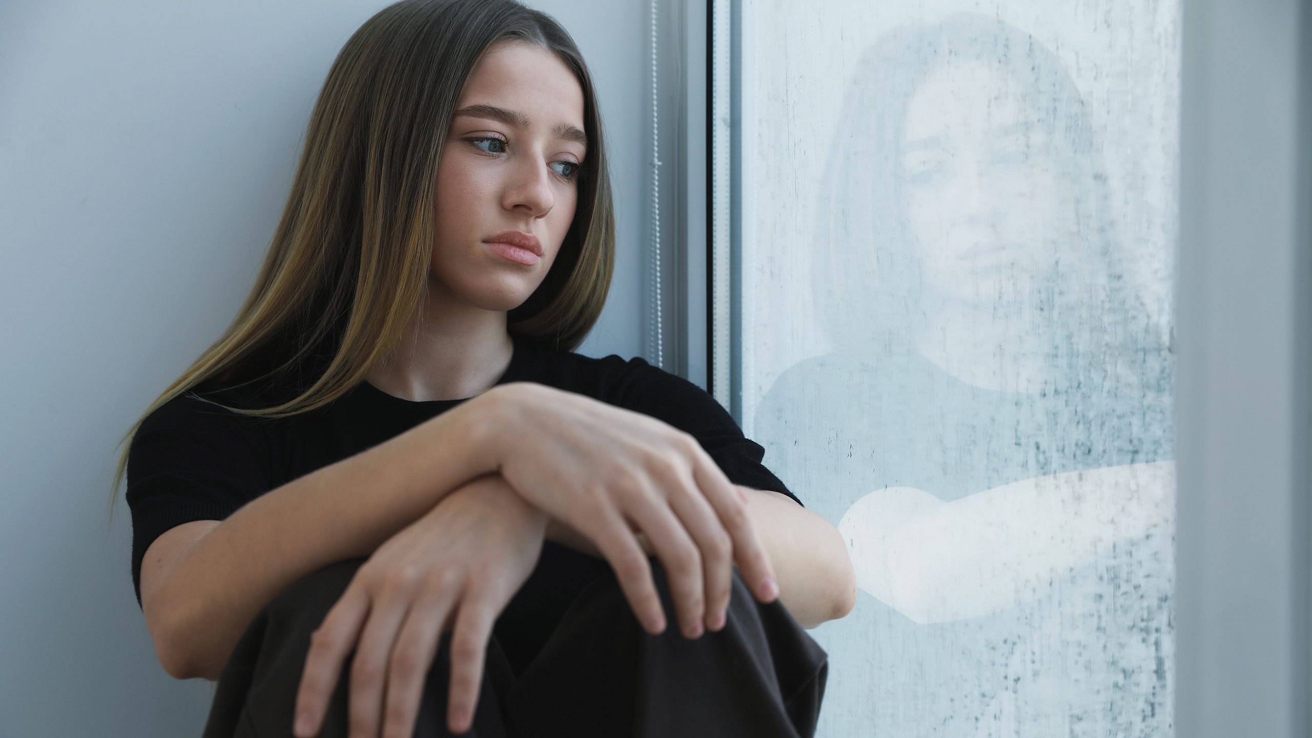 Depressed teenage girl near window at home