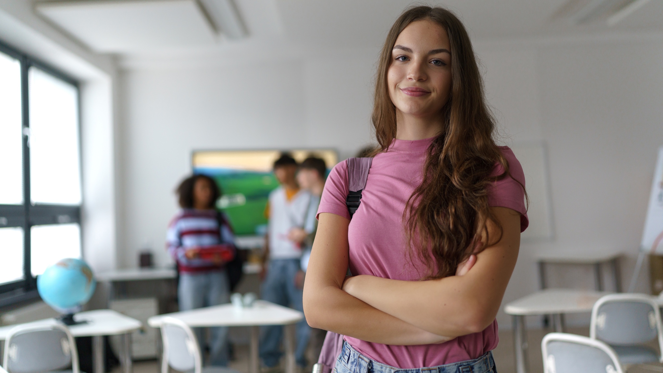 Confident teen student standing in modern classroom.