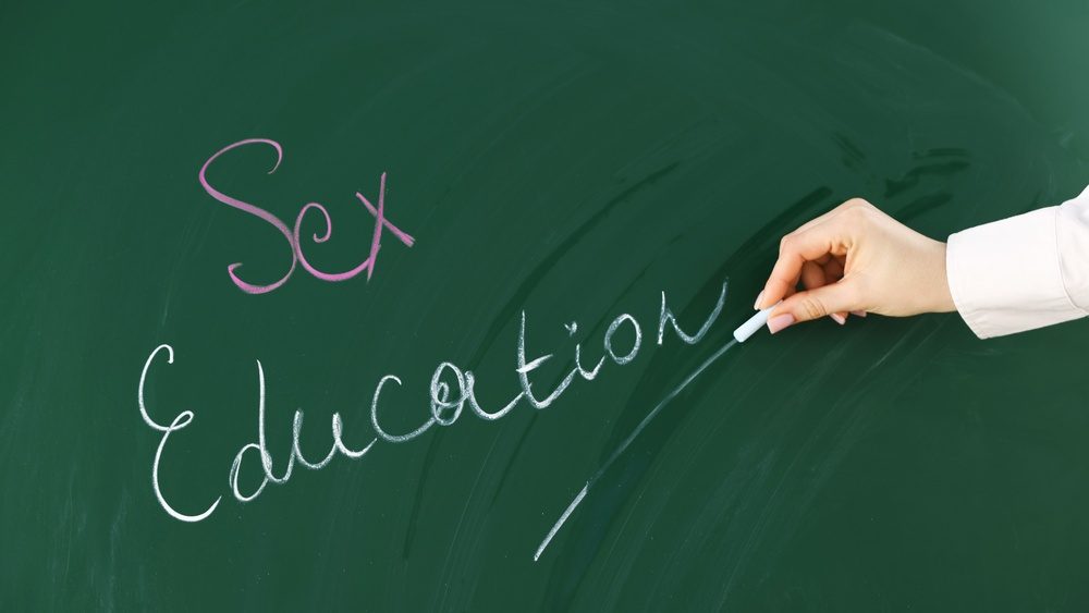 Woman writing words Sex Education on green chalkboard, closeup