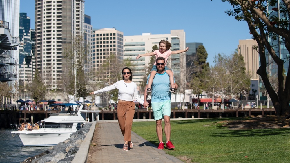 Happy family with little child son walking in modern urban city. outdoors against city landscape in San Diego.