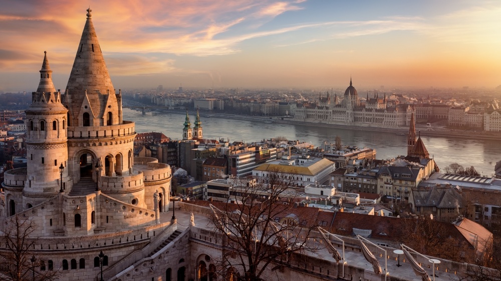 The Fisherman's Bastion from above with Hungarian Parliament building and River Danube during a golden sunrise in Budapest