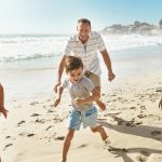 Running, playing and happy family at a beach with fun, bonding and freedom on summer, vacation and holiday. Travel, energy or excited kids with parents at ocean for adventure, journey or race in Bali