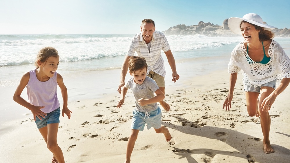 Running, playing and happy family at a beach with fun, bonding and freedom on summer, vacation and holiday. Travel, energy or excited kids with parents at ocean for adventure, journey or race in Bali