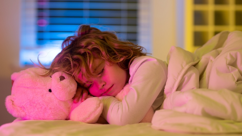 Nighttime sleep. Kid sleeping on bed at home. Bedtime, kids sleeps with a toy teddy bear. Child asleep on pillow, having healthy sleep.