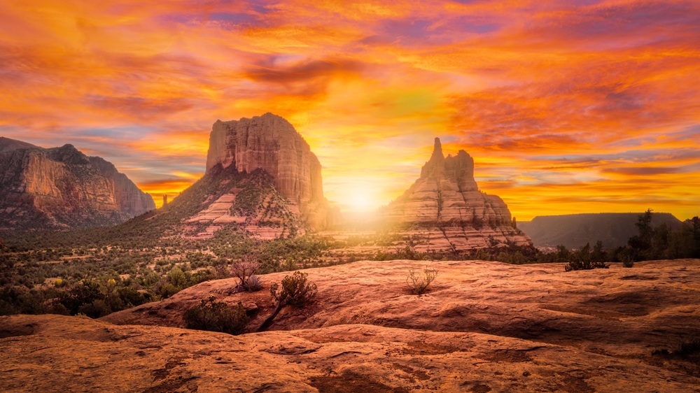 A breathtaking sunset over Sedona's red rock formations with vibrant orange and pink skies.