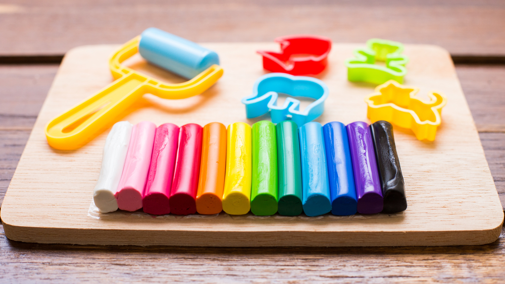 Plasticine and tools are on wooden background.