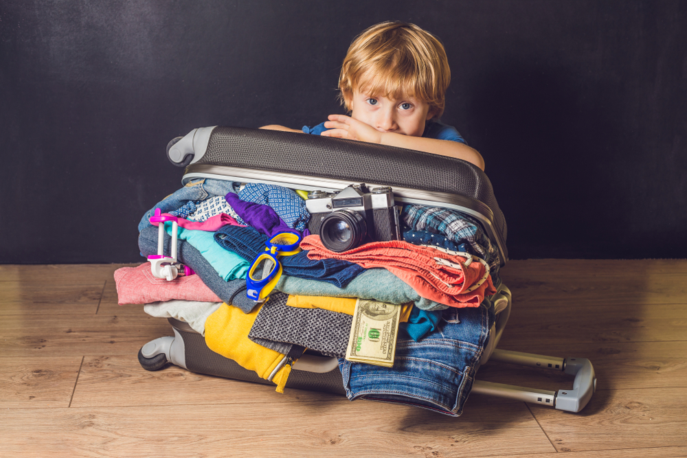 Baby boy and Travel Suitcase. Kid and Luggage Packed for Vacation Full of Clothes, Child and Family Trip