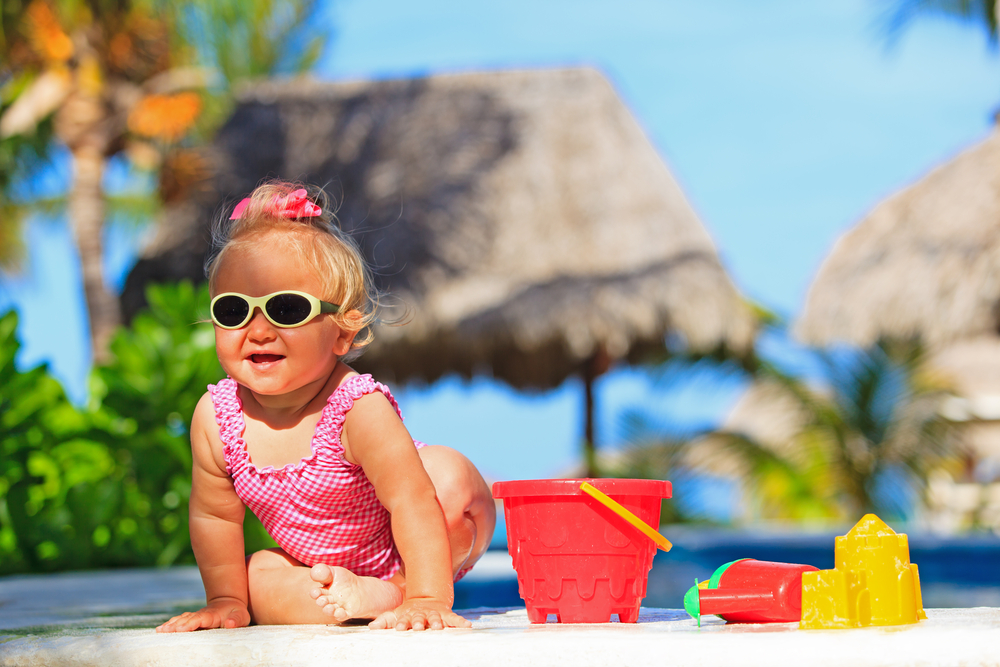 cute toddler girl playing in swimming pool at tropical beach