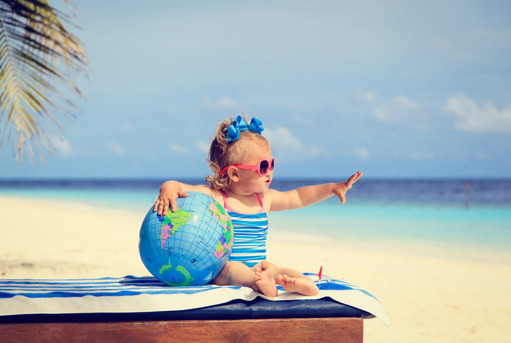little girl with globe and toy plane on beach, kids travel